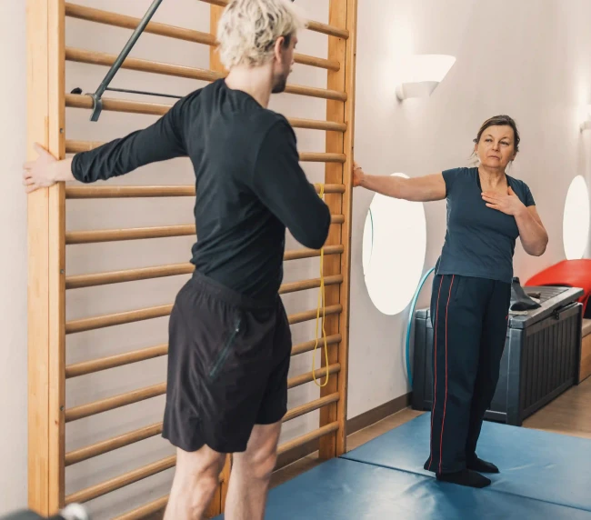 Personal Trainer zeigt Aufwärmübung gemeinsam mit der Kundin vor