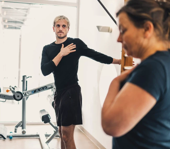 Personal Trainer zeigt Aufwärmübung gemeinsam mit der Kundin vor