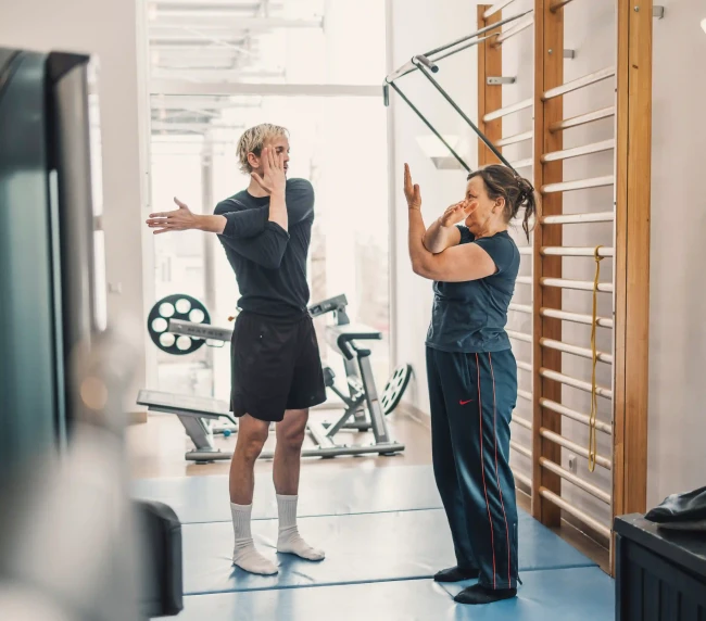 Personal Trainer zeigt Dehnübung gemeinsam mit der Kundin vor