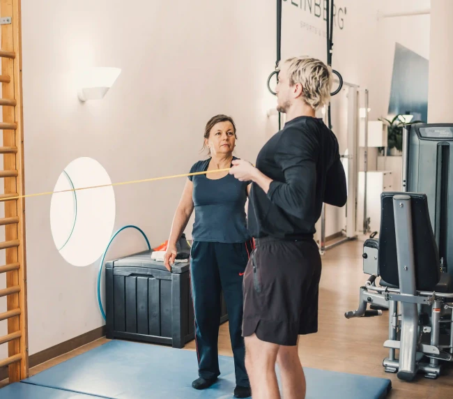 Personal Trainer zeigt Übung mit dem Widerstandsband der Kundin vor