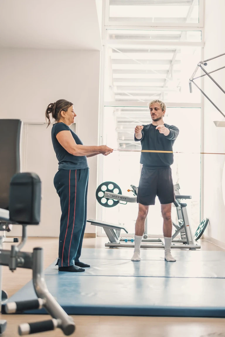 Personal Trainer zeigt Übung mit dem Widerstandsband der Kundin vor