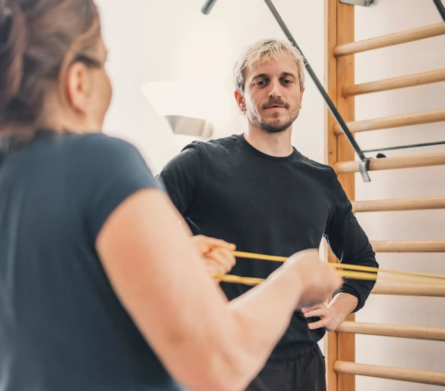 Personal Trainer beobachtet Übung von der Kundin mit Widerstandsband