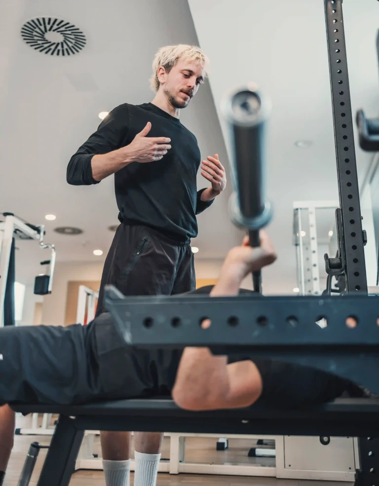 Personal Trainer erklärt Übung des Kunden auf der Langbank