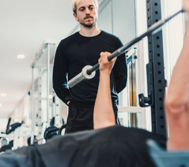 Personal Trainer beobachtet Übung des Kunden auf der Langbank