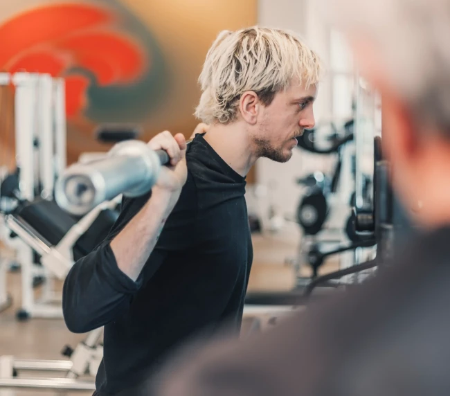 Personal Trainer zeigt Übung mit der Langhantel vor