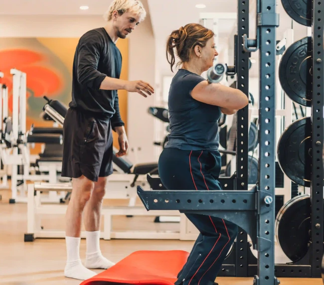 Personal Trainer korrigiert Kundin bei Übung mit der Langhantel