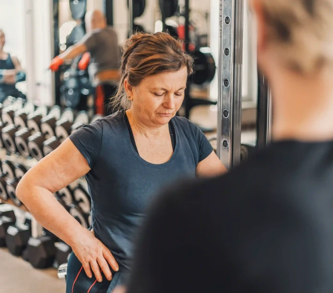 Personal Trainer beobachtet Übung bei der Kundin mit der Langhantel