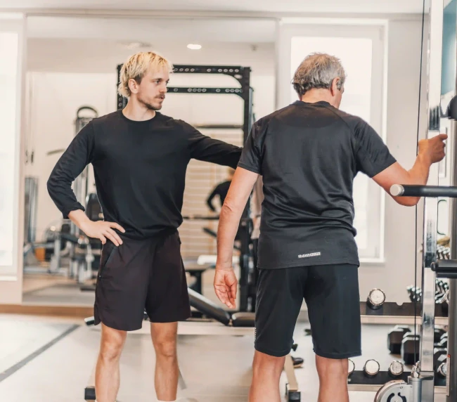 Personal Trainer erklärt dem Kunden Beinübung am Seilzug