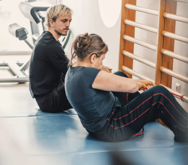 Personal Trainer zeigt Aufwärmübung gemeinsam mit der Kundin vor